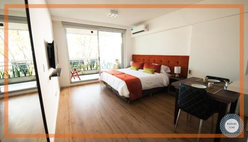 1 dormitorio con 1 cama, escritorio y ventanas en Medrano Kind en Buenos Aires