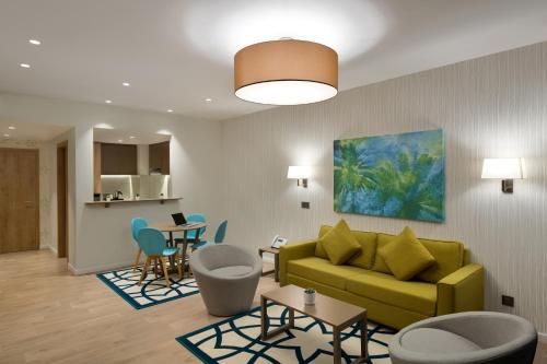 a living room with a yellow couch and chairs at Adagio Jeddah City Center in Jeddah