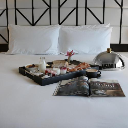 a tray of food on a bed with a book at Mövenpick Hotel Auckland in Auckland