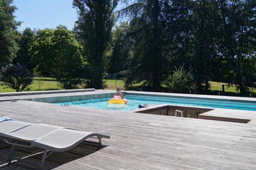 a child in a swimming pool with a raft at Le Petit Moulin in Faverelles