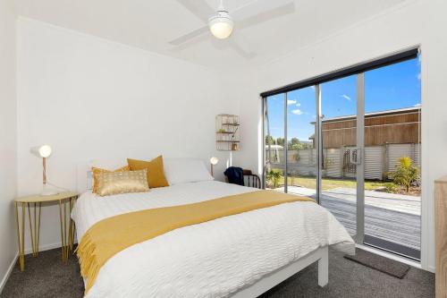 ein Schlafzimmer mit einem Bett und einem großen Fenster in der Unterkunft The Sunshine Bungalow - Mangawhai Heads Home in Mangawhai