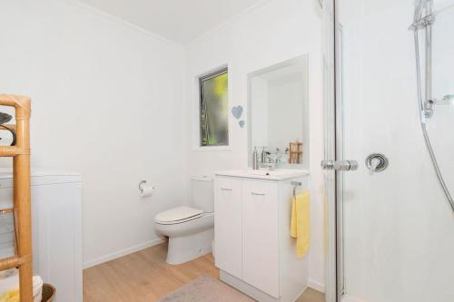 ein weißes Badezimmer mit Toilette und Dusche in der Unterkunft The Sunshine Bungalow - Mangawhai Heads Home in Mangawhai
