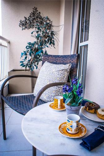 a table with two cups and a plate of food on a balcony at Terraço Harmony Flats GRU in Guarulhos