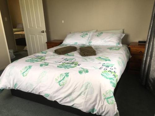uma cama com lençóis brancos e folhas verdes em Irishman Retreat em Twizel