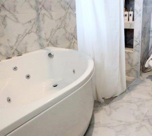 a bathroom with a white tub and a white shower curtain at Hotel Chuan Chom The High Resort Saraburi - SHA Plus in Sara Buri