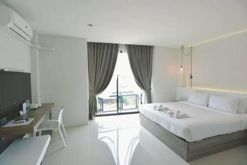 a bedroom with a bed and a desk and a window at Hotel Chuan Chom The High Resort Saraburi - SHA Plus in Sara Buri