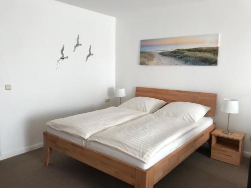 a bedroom with a bed with white sheets and birds on the wall at Steiner Strandappartements Appartement 206 Süd- Landseite in Stein