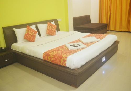 a large bed in a room with a chair at Hotel Sunrise N Resorts in Nagpur