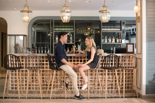 a man and woman sitting on a bench at a bar at Sawaddi Patong Resort & Spa by Tolani in Patong Beach