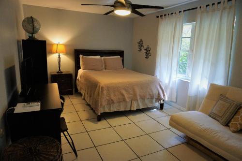 a bedroom with a bed and a couch and a fan at JUPITER WATERFALLS - NEWLY UPDATED - TIKI HUT, FIRE PIT, KITCHEN, POOL HEATER and MORE in Jupiter