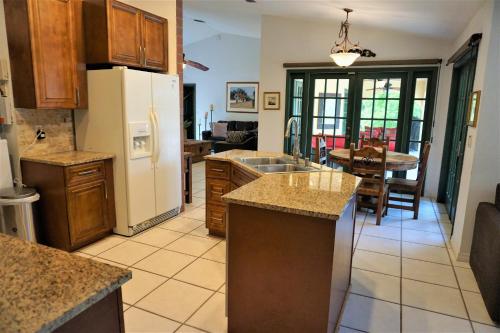 a kitchen with a white refrigerator and a table at JUPITER WATERFALLS - NEWLY UPDATED - TIKI HUT, FIRE PIT, KITCHEN, POOL HEATER and MORE in Jupiter