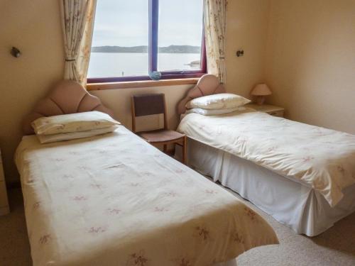 two beds in a room with a window at 2 Bayview Bungalow in Poolewe