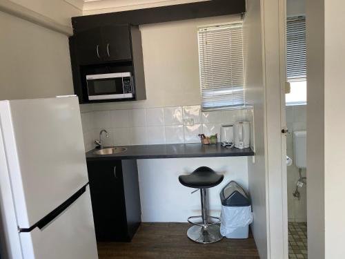a kitchen with a refrigerator and a sink at Hervey Bay Motel in Hervey Bay