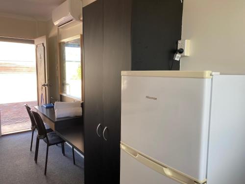 a kitchen with a refrigerator and a table at Hervey Bay Motel in Hervey Bay
