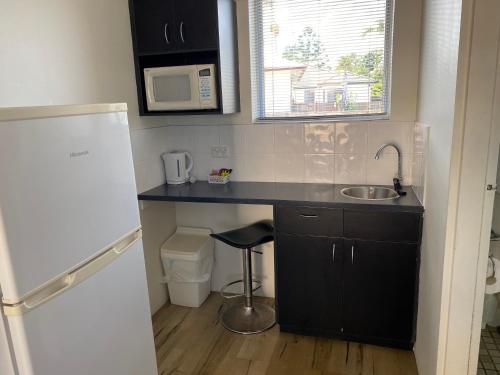 uma pequena cozinha com um lavatório e um micro-ondas em Hervey Bay Motel em Hervey Bay
