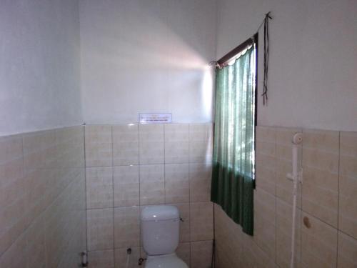 a bathroom with a toilet and a shower with a window at Latansa inn in Karimunjawa