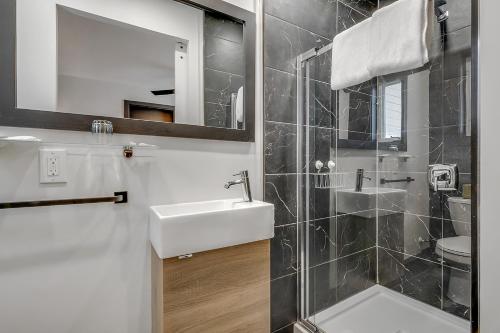 een badkamer met een wastafel en een douche met een spiegel bij Motel Lévis in Lévis