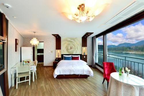 a bedroom with a bed and a balcony with a view at Moonlight Blue Pension in Gapyeong
