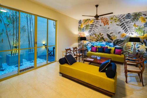 a living room with a yellow couch and a mural at Rosmead Place by Thilanka in Colombo