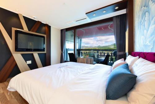 a bedroom with a large white bed with a large window at Moonlight Blue Pension in Gapyeong