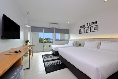 a hotel room with two beds and a flat screen tv at Ruenthip Pattaya in North Pattaya