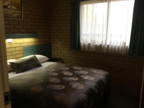 a bedroom with a bed and a window at Sunrise Motel in Barooga