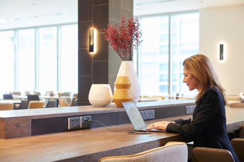 a woman sitting at a table with a laptop at Holiday Inn Express Melbourne Southbank by IHG in Melbourne