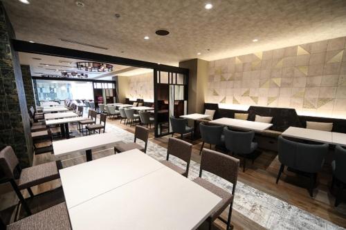 a dining room with white tables and chairs at Shin Osaka Esaka Tokyu REI Hotel in Suita