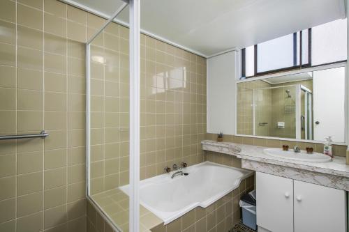 a bathroom with a tub and a sink and a mirror at Tasman Towers 12 3 Munster Street in Port Macquarie