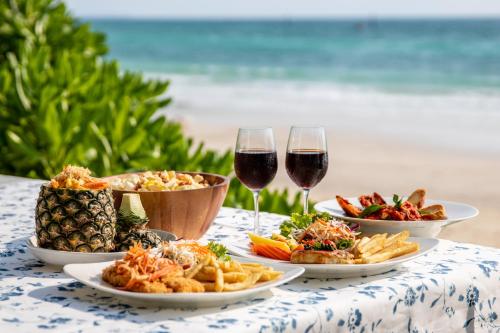 a table with three plates of food and two glasses of wine at Xanadu Beach Resort in Ko Larn