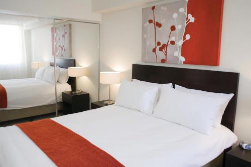 トゥーンバにあるToowoomba Central Plaza Apartment Hotel Officialのベッドが2つと鏡があるホテルの部屋