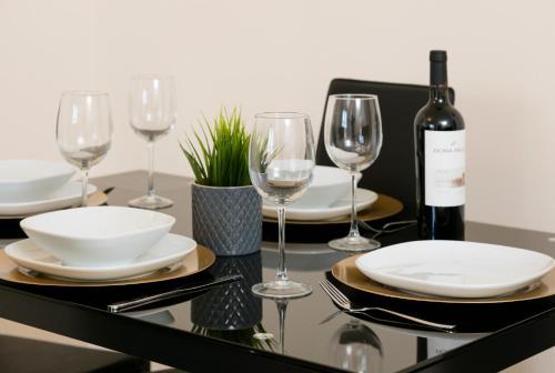 a table with glasses and plates and a bottle of wine at 3 Beds 2BR Apartment BHX City Centre NEC Solihull Ideal for Contractors & Insurance in Birmingham