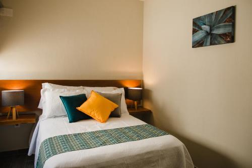 a bedroom with a bed with colorful pillows at casa AGAVE x Santiago de Tequila in Tequila