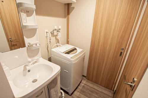 a bathroom with a sink and a washing machine at UCHI Living stay Odori 11 in Sapporo