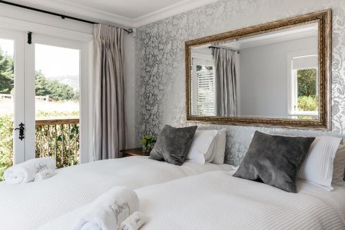 two beds in a bedroom with a mirror on the wall at Cottage 103 in Waikanae