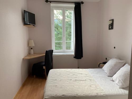 een slaapkamer met een bed, een raam en een bureau bij L’air du temps in Beauzac