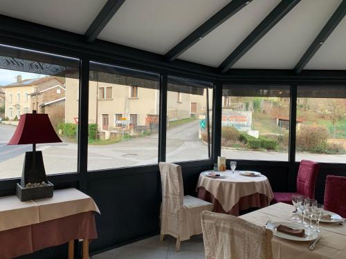 a dining room with two tables and windows at L’air du temps in Beauzac
