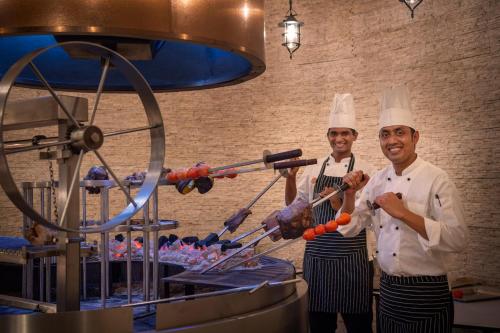 two chefs standing in a kitchen preparing food at Emerald Maldives Resort & Spa-Deluxe All Inclusive in Raa Atoll