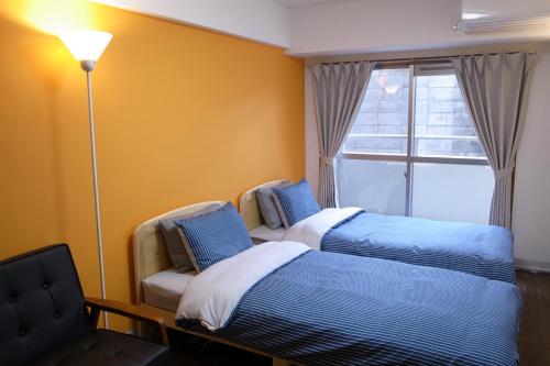 um quarto com 2 camas, uma cadeira e uma janela em KYOTO SANJO Inn 京都三条イン em Quioto
