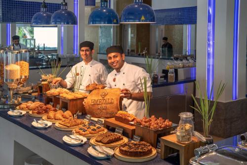 two chefs are standing behind a buffet of food at Emerald Maldives Resort & Spa-Deluxe All Inclusive in Raa Atoll