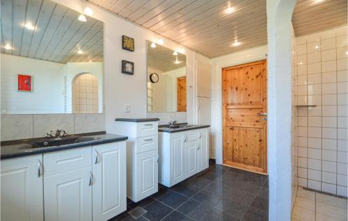 a bathroom with white cabinets and a wooden door at Awesome Home In Bredebro With Kitchen in Ballum