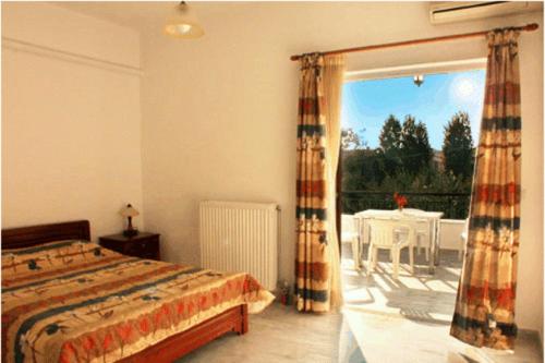 a bedroom with a bed and a patio with a table at Studios Akrogiali in Kyparissia