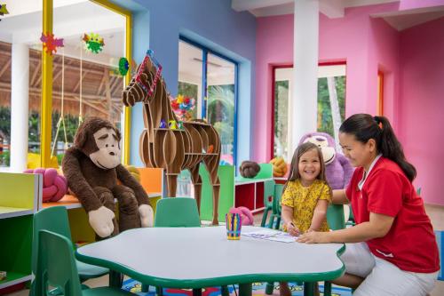 a woman and a little girl sitting at a table in a classroom at Emerald Maldives Resort & Spa-Deluxe All Inclusive in Raa Atoll