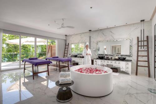 a woman standing in a room with a large tub at Emerald Maldives Resort & Spa-Deluxe All Inclusive in Raa Atoll