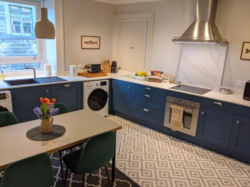a kitchen with blue cabinets and a table with flowers on it at Central Hawick spacious stylish flat with log burner in Hawick