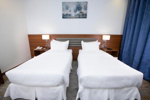 two beds in a hotel room with blue curtains at Eva Hotel in Jeddah