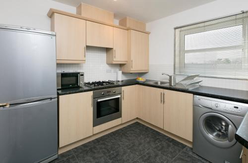 a kitchen with wooden cabinets and a stainless steel appliance at 3 Beds 2BR Apartment BHX City Centre NEC Solihull Ideal for Contractors & Insurance in Birmingham