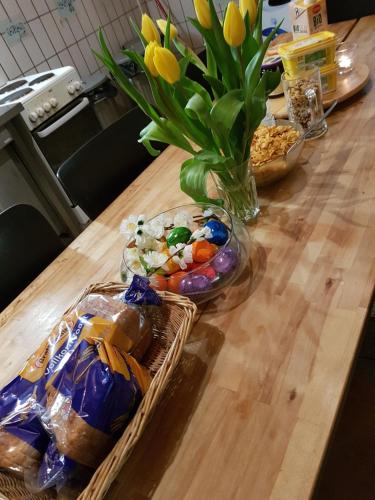 einen Holztisch mit einer Vase aus Blumen und Snacks in der Unterkunft Penthouse Backpackers in Osnabrück