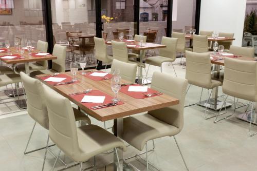a dining room with wooden tables and white chairs at ibis Curitiba Shopping in Curitiba