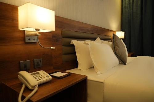 a hotel room with a phone next to a bed at Eva Hotel in Jeddah